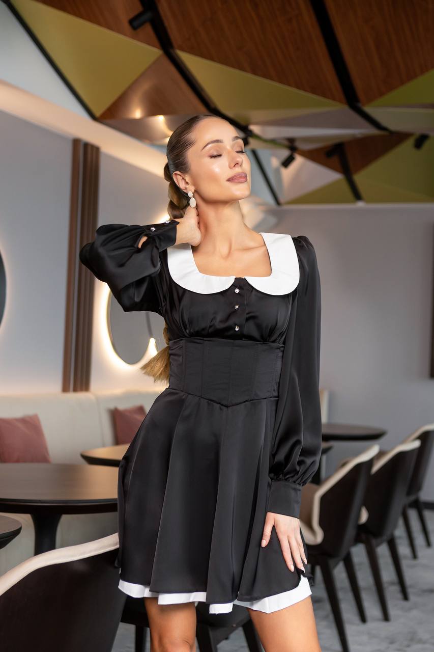 Woman in a black dress with white collar and cuffs in a modern restaurant setting