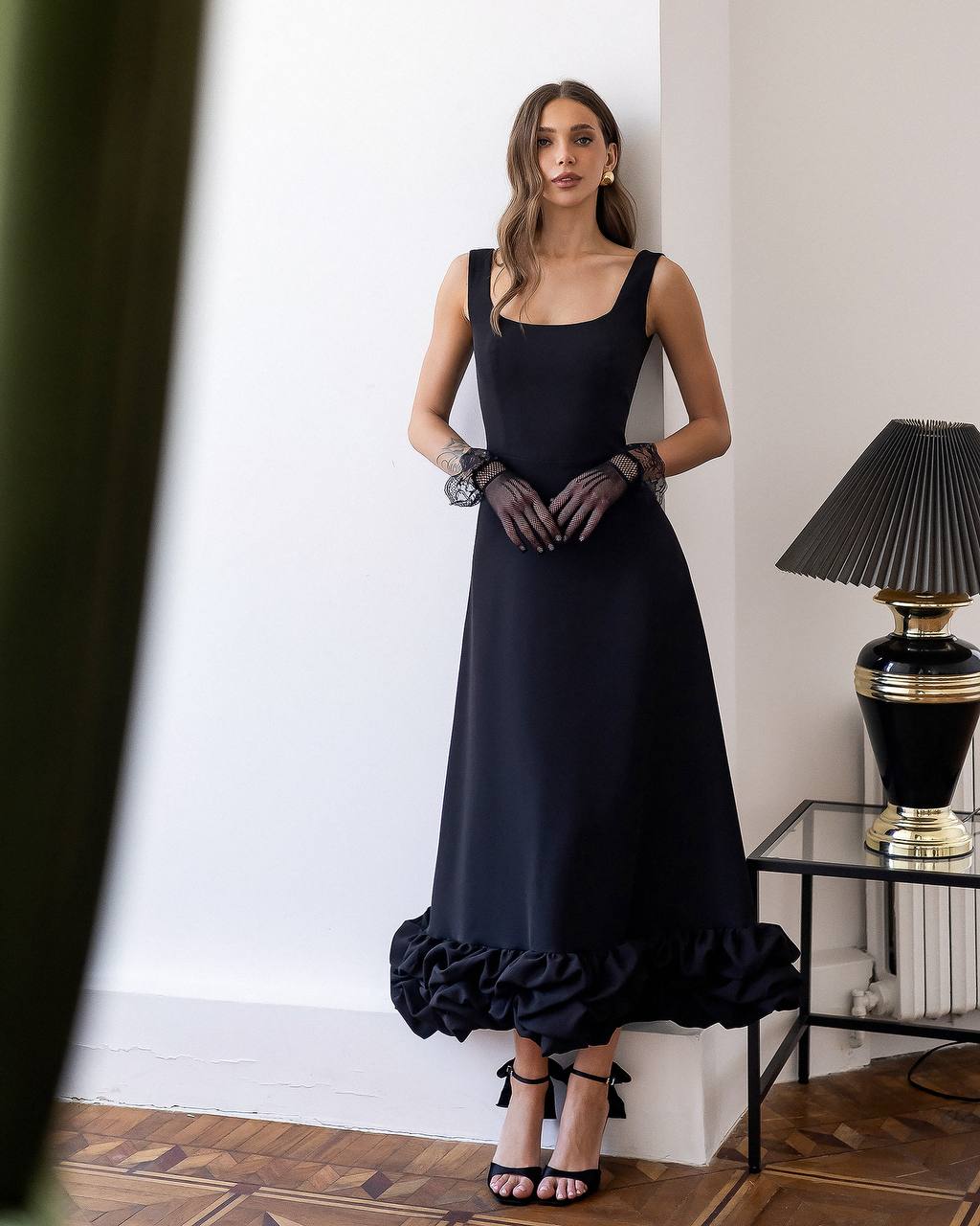 Woman wearing a black dress with ruffled hem in an elegant room.