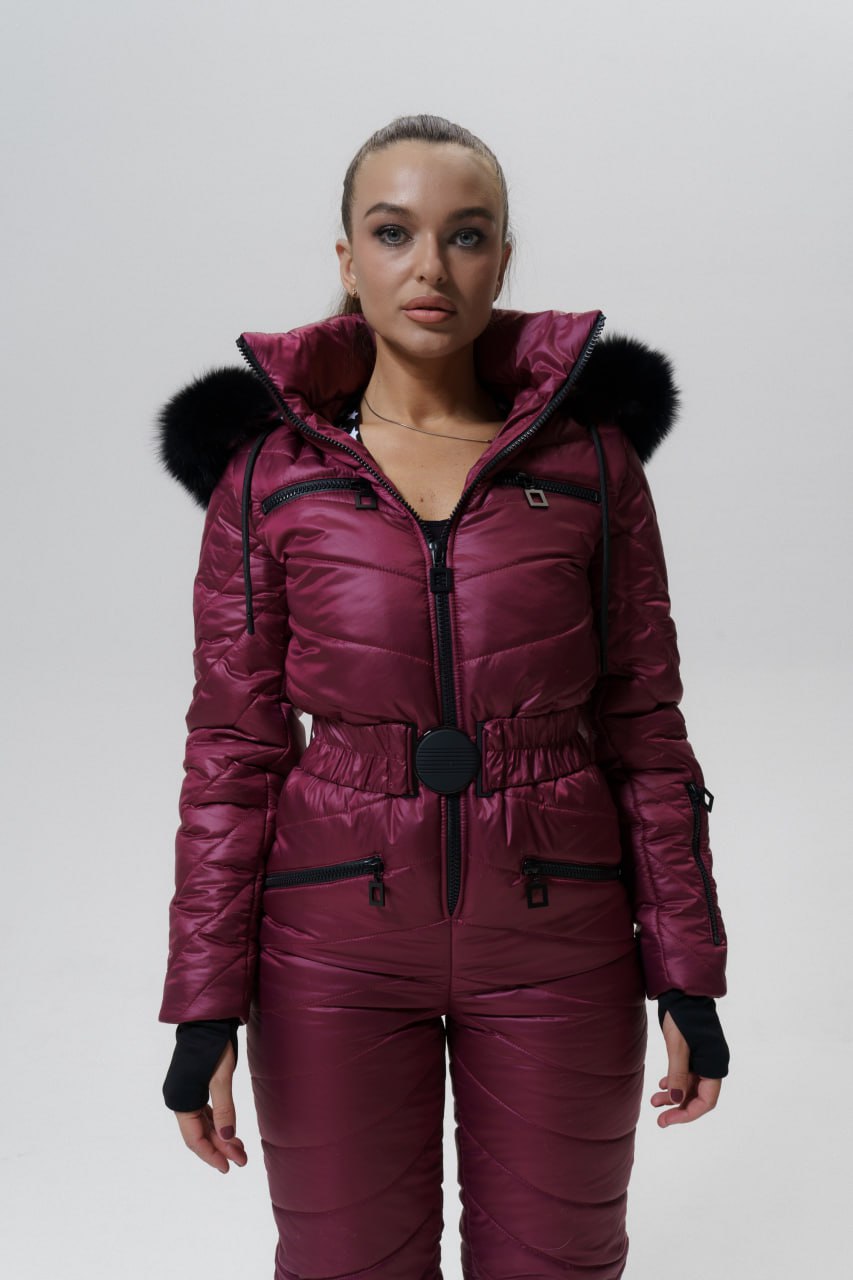 Person wearing a maroon puffer suit with black fur trim on a white background