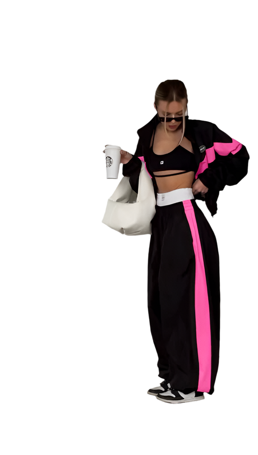 Person wearing a black and pink tracksuit with a white background
