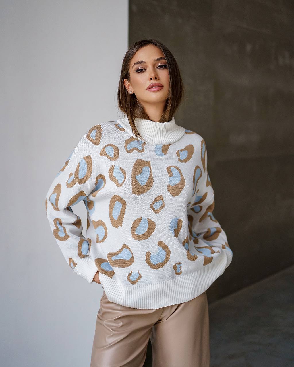 Woman wearing a white sweater with colorful abstract patterns against a neutral background