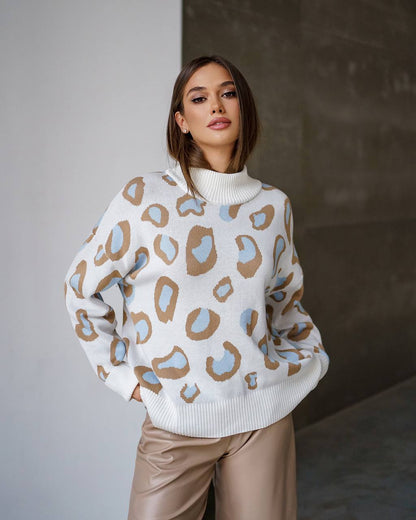 Woman wearing a white sweater with colorful abstract patterns against a neutral background