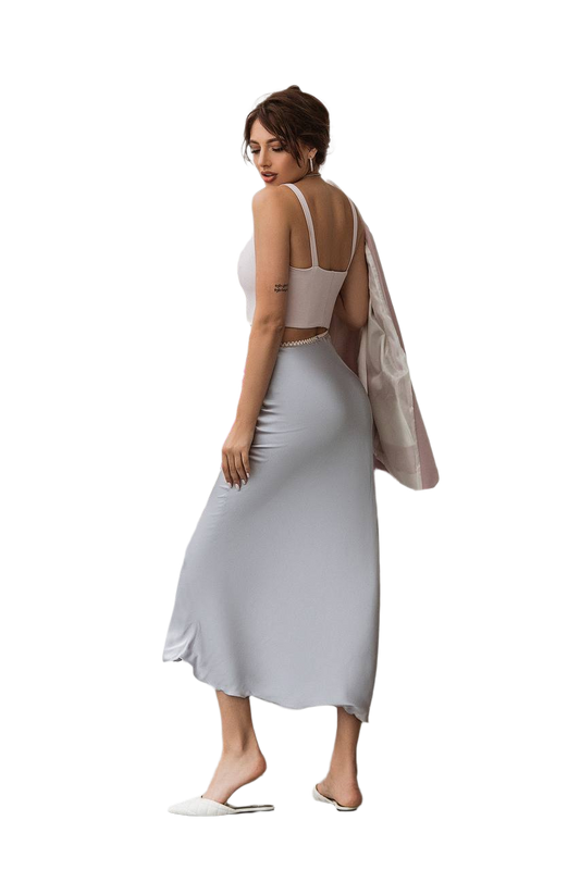 Woman wearing a white top and light gray skirt with a beige cardigan on a white background