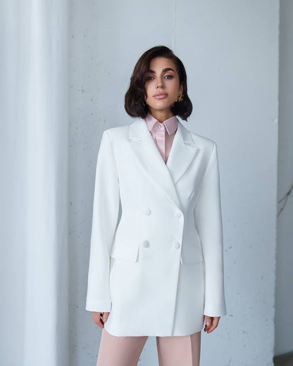 Woman wearing a white blazer over a pink shirt against a light gray background