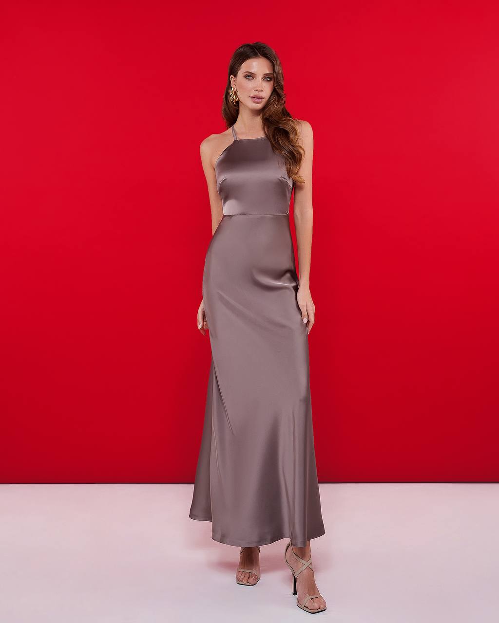 Woman wearing a long satin dress against a red background