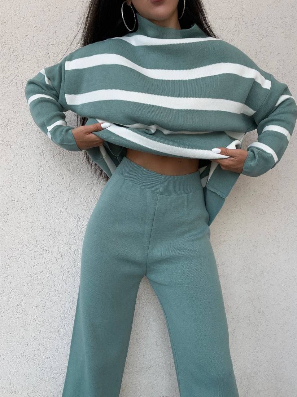 Person wearing a green and white striped sweater and matching pants against a light gray background