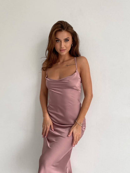 Woman wearing a pink satin dress against a plain background
