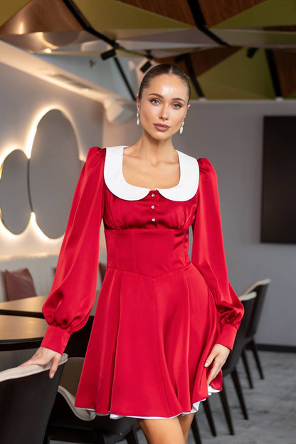 Woman in a red dress with white collar standing in a modern interior setting