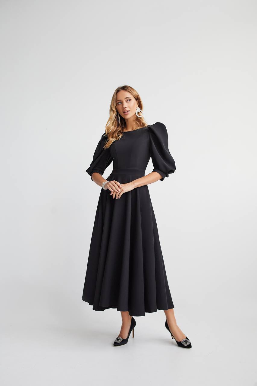 Woman wearing a black dress with puffed sleeves on a white background