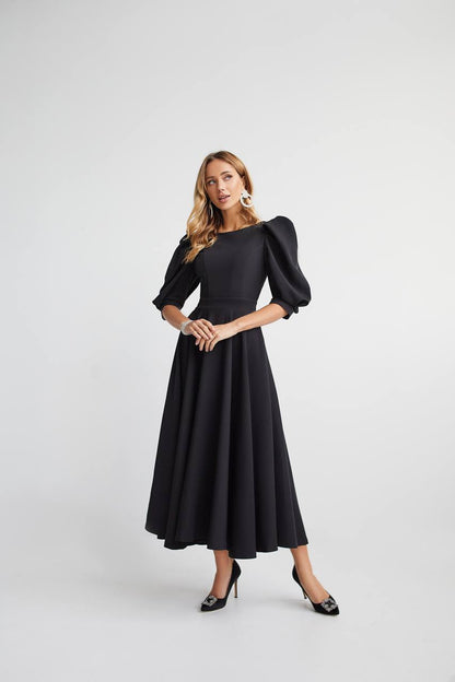 Woman wearing a black dress with puffed sleeves on a white background