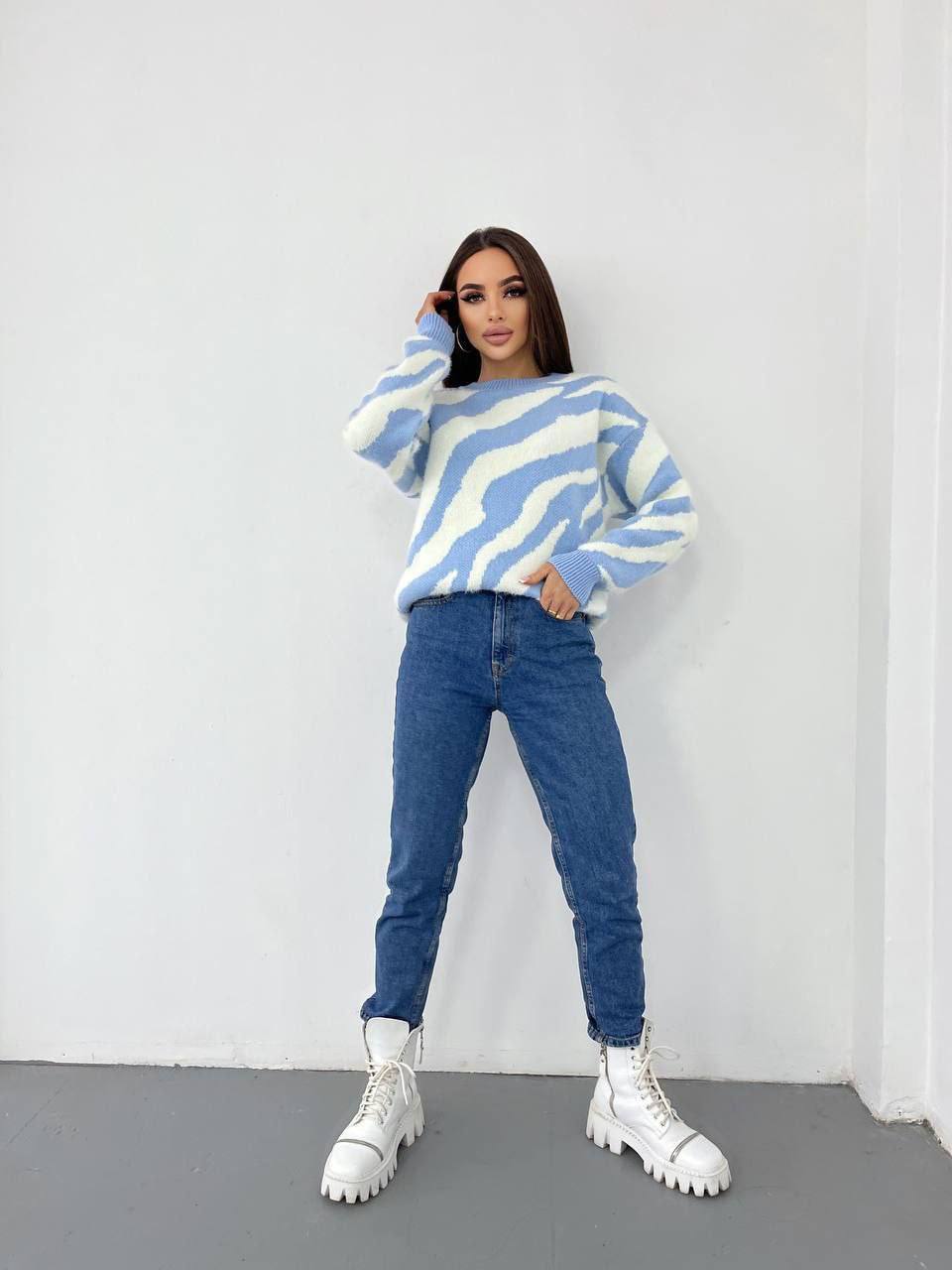Person wearing a blue and white striped sweater with jeans and white shoes against a white background