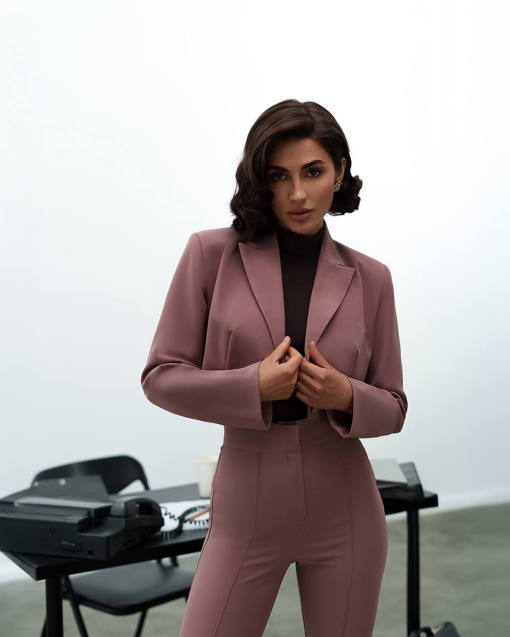 Woman in a pink suit standing in an indoor setting with a blurred background