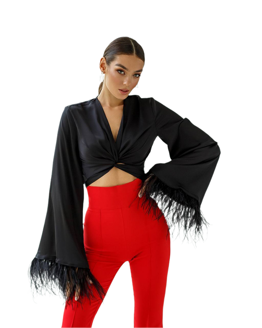 Woman wearing a black fringed top and red pants on a white background