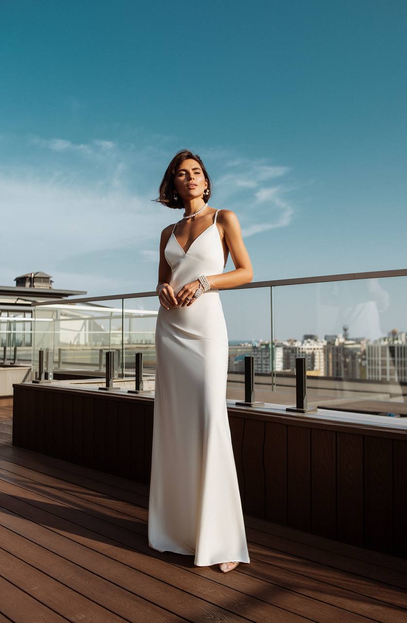 Woman in a white dress standing on a rooftop with a cityscape in the background