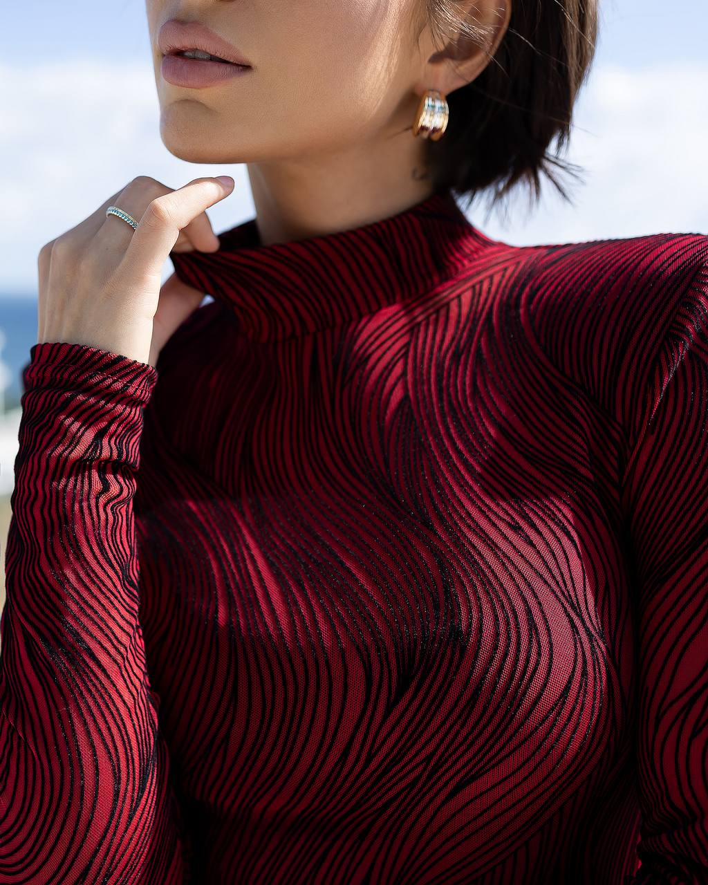 Close-up of a person wearing a red patterned long-sleeve top with a blurred background