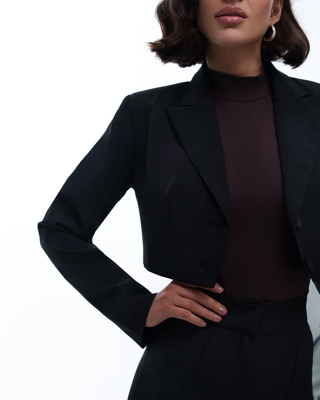 Person wearing a black blazer over a dark top on a white background