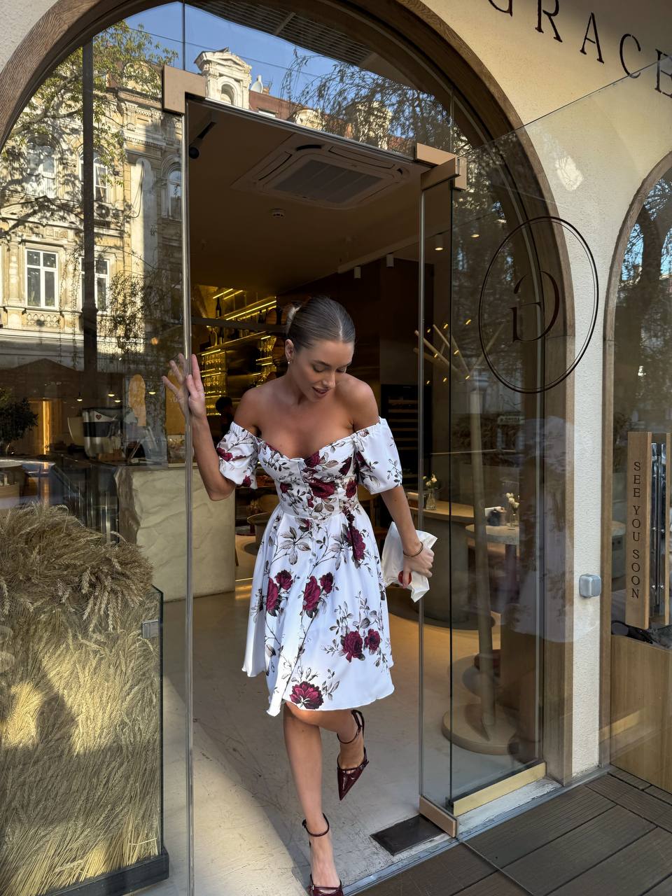 Woman in a floral dress walking out of a store with 'Grace' branding.