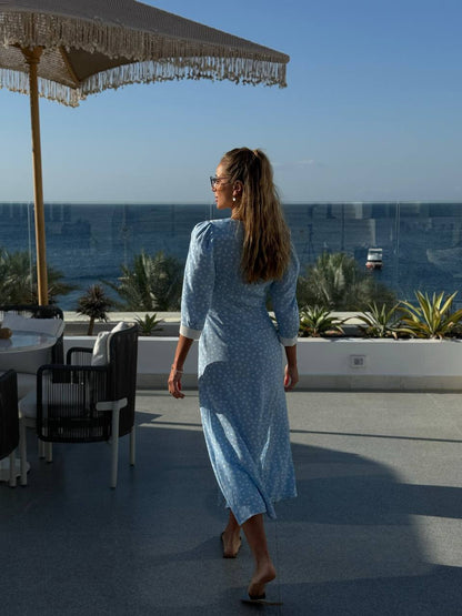 Woman in a blue dress standing on a rooftop with ocean view