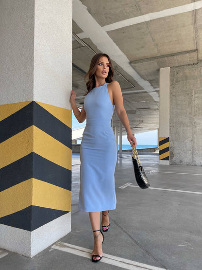 Woman in a light blue dress walking under a concrete overpass.