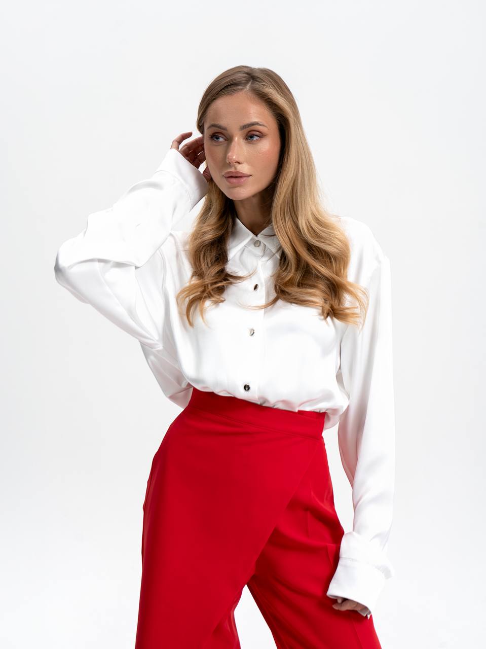 Woman wearing a white blouse and red pants on a white background