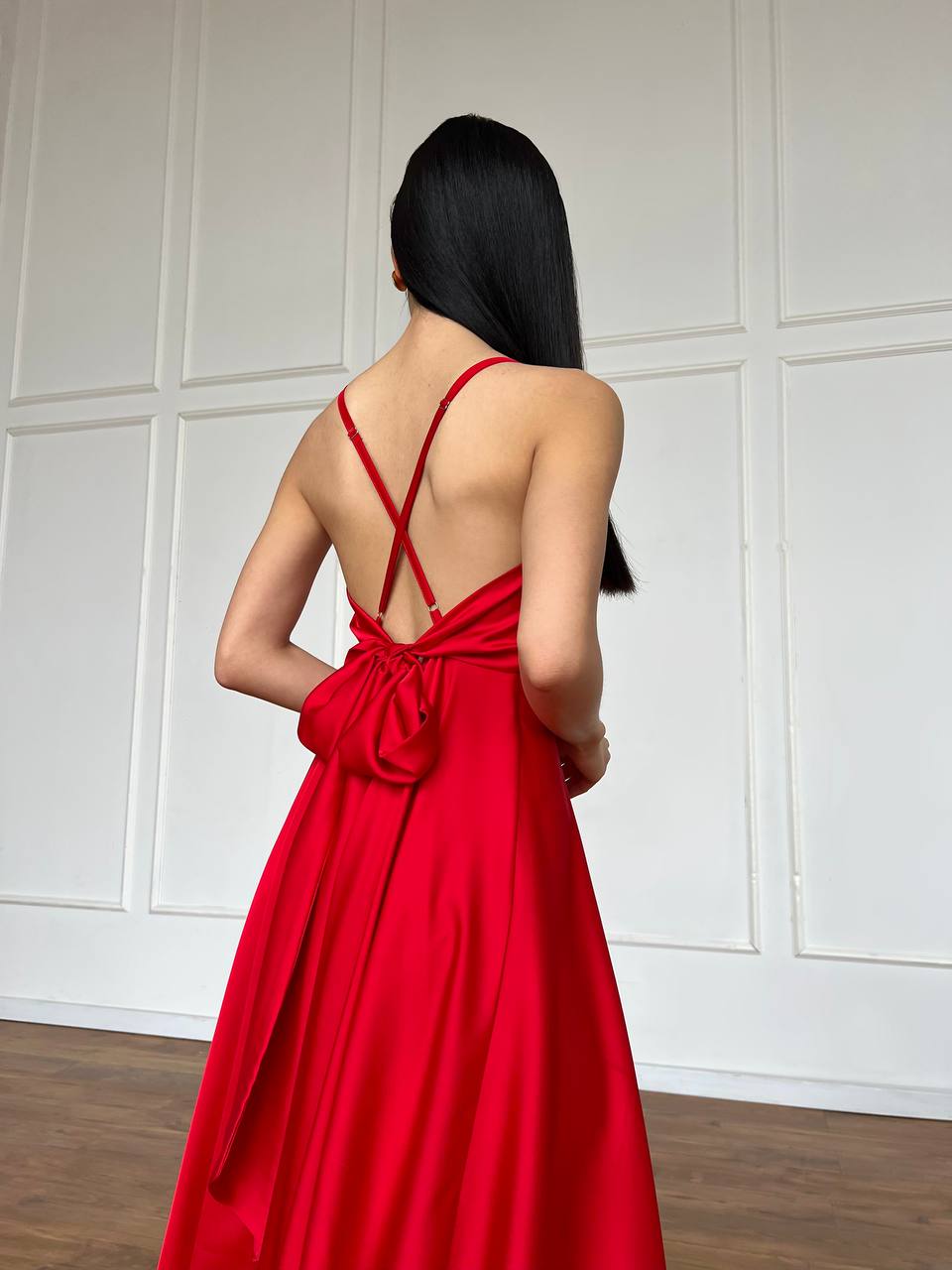 Woman wearing a red dress with a white paneled wall background