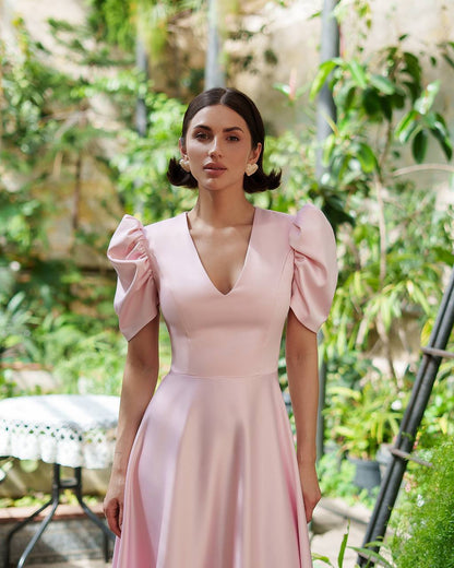 Woman wearing a pink dress standing in a garden setting