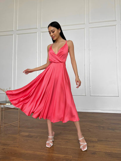 Woman in a pink dress standing in a room with wooden floor and white paneled walls.