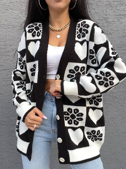 Person wearing a black and white patterned cardigan over a white top and blue jeans.