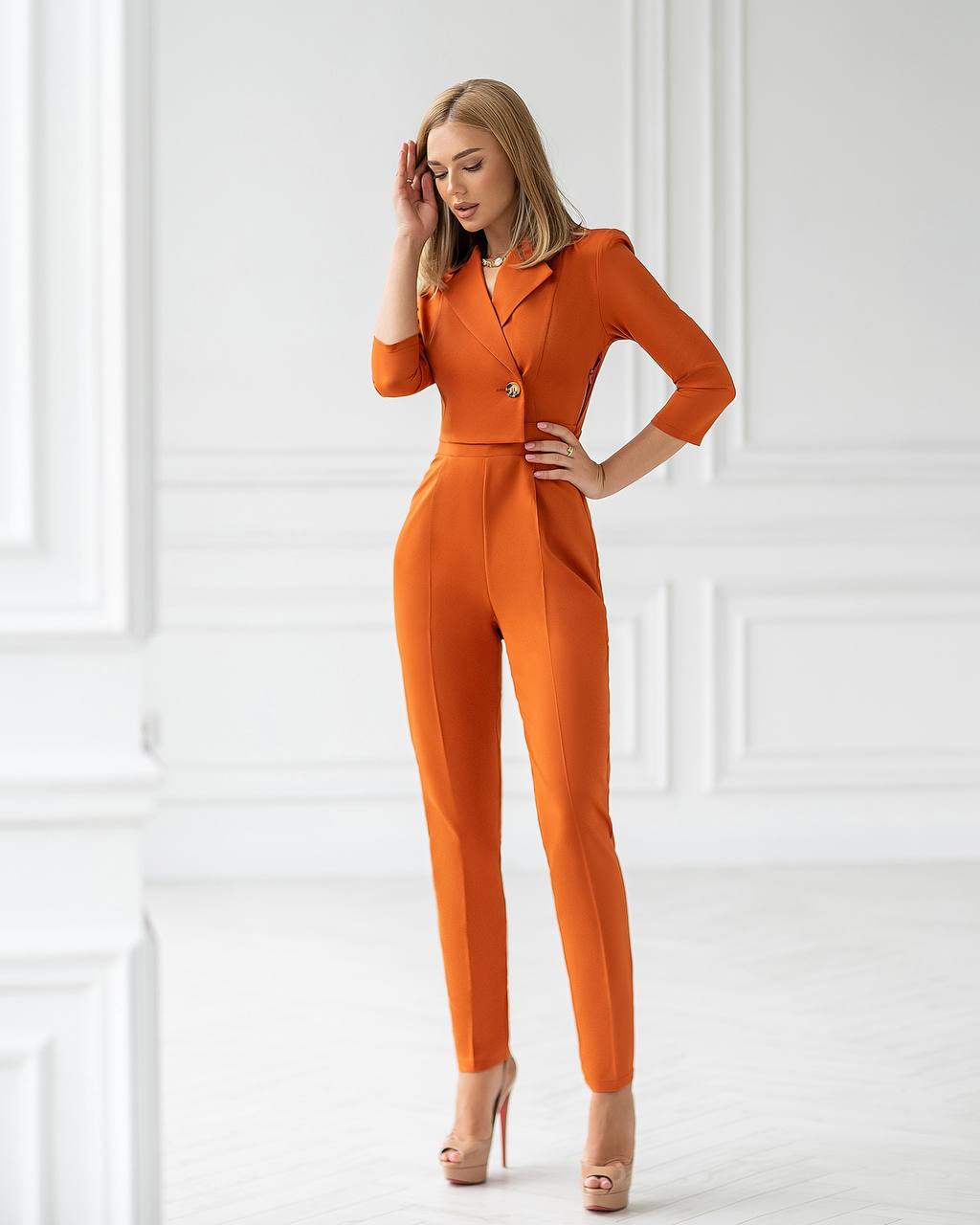 Woman wearing an orange jumpsuit against a white wall
