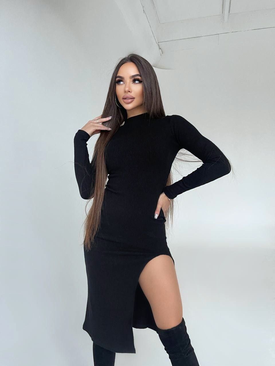 Woman wearing a black outfit with a slit skirt against a white background