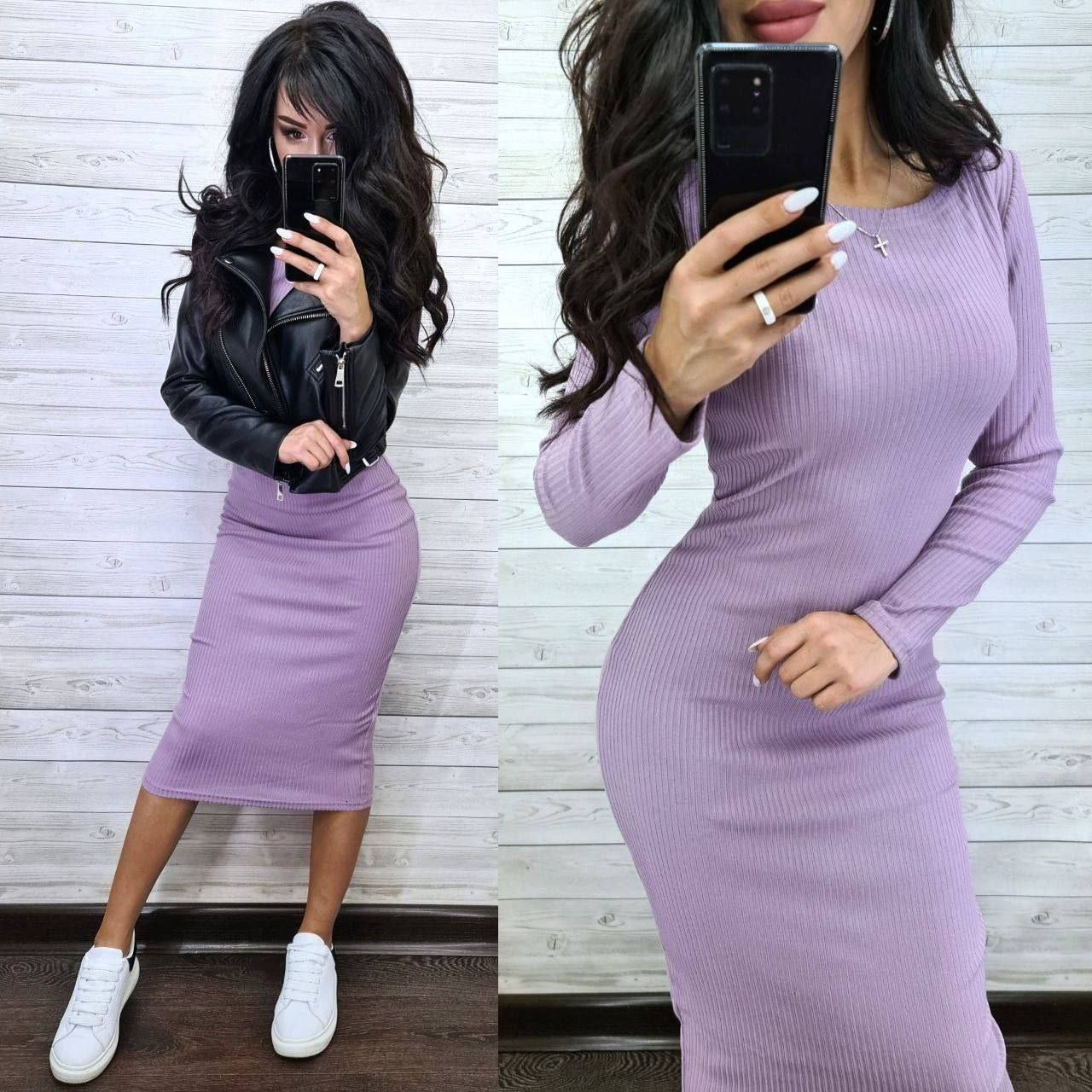 Woman wearing a purple ribbed dress with a black leather jacket and white sneakers, taking a mirror selfie.