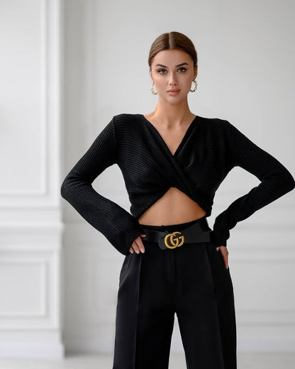 Woman wearing a black outfit with a Gucci belt against a white wall