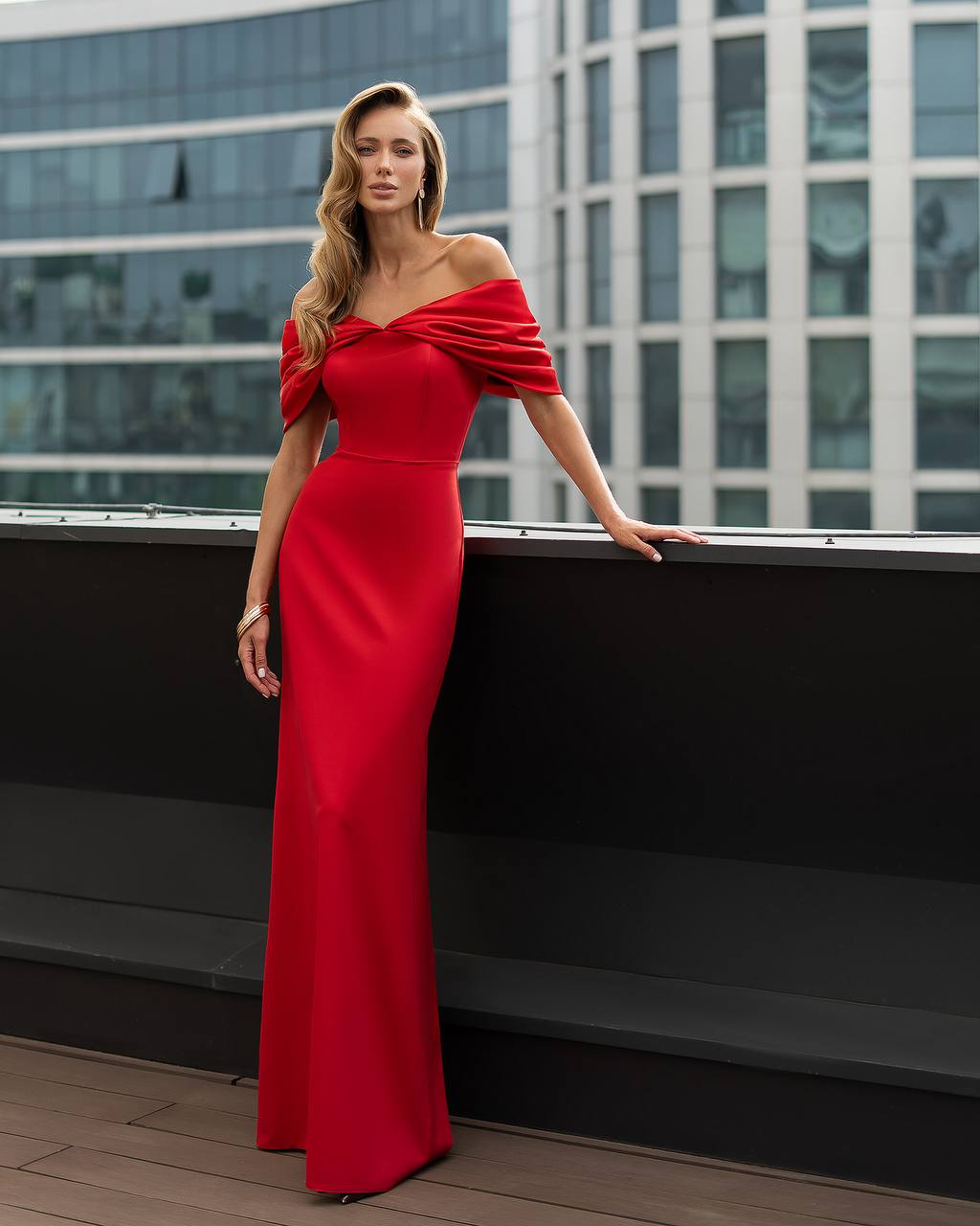 Woman in a red dress standing on a rooftop with cityscape background
