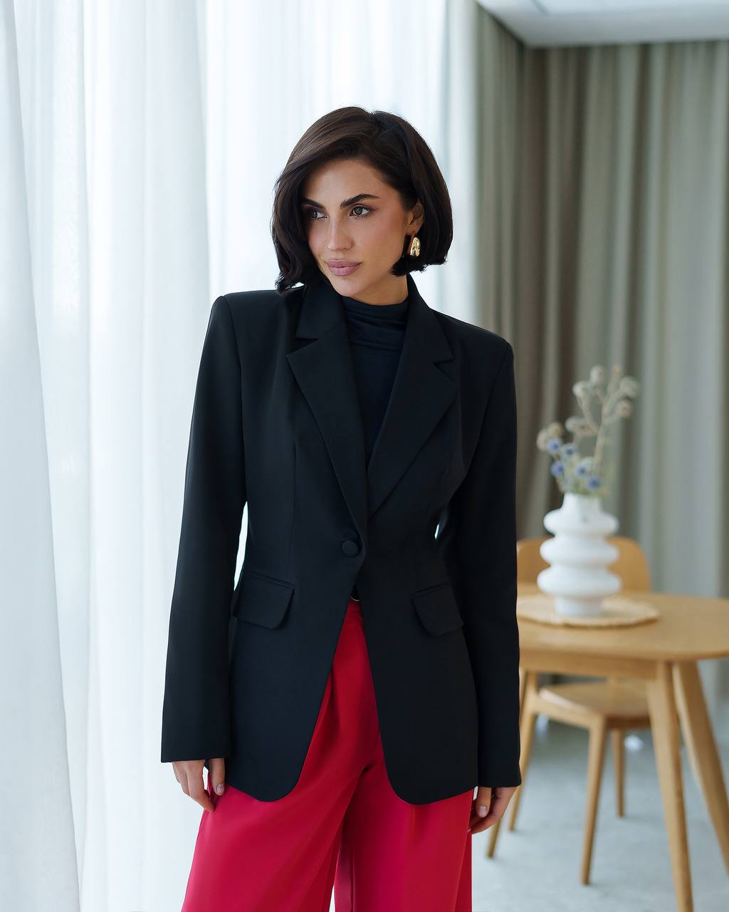 Woman wearing a black blazer and red pants in an indoor setting