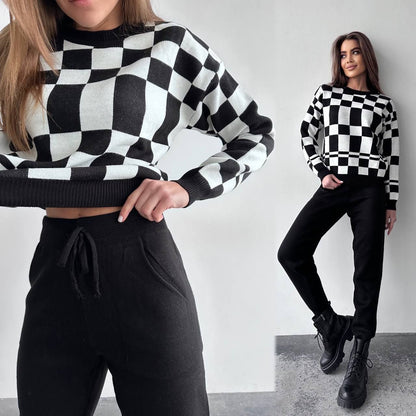 Two women wearing black and white checkered sweaters with black pants against a plain background.