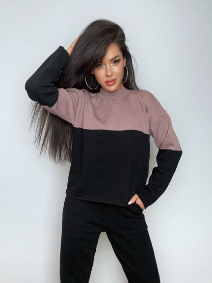 Woman wearing a two-tone sweater with black and pink colors against a white background
