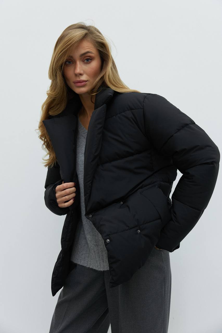 Woman wearing a black puffer jacket against a white background
