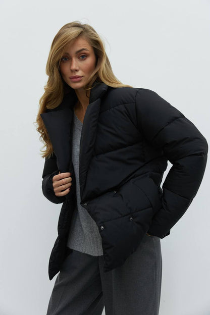 Woman wearing a black puffer jacket against a white background