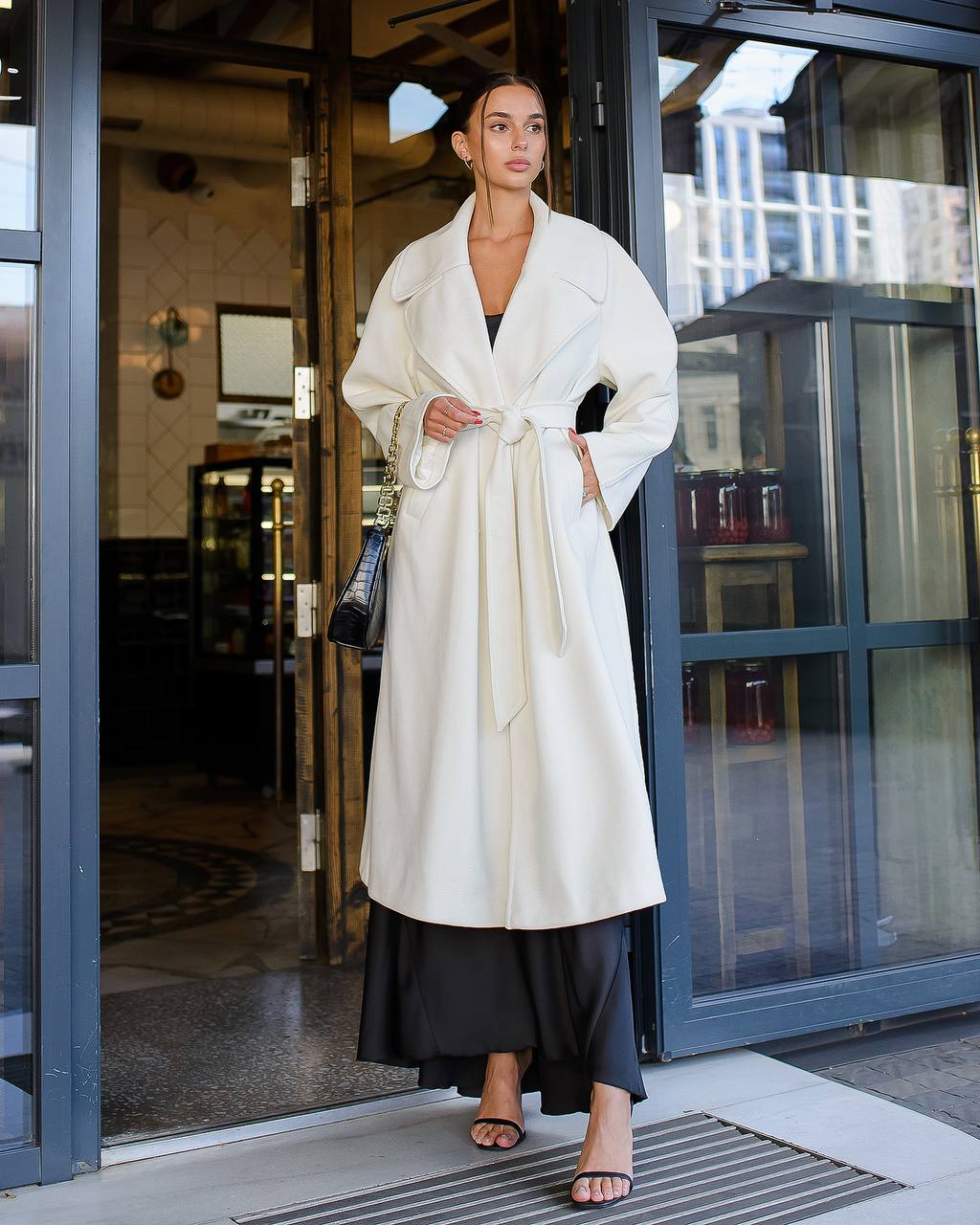 Woman in a white coat standing outside a building