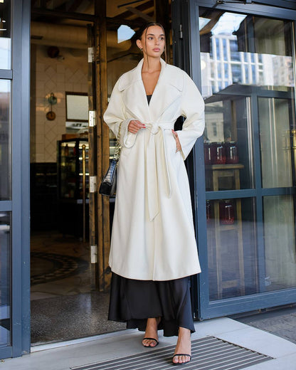 Woman in a white coat standing outside a building