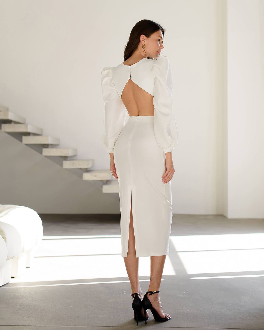 Woman wearing a white dress with cut-out design in a minimalistic setting