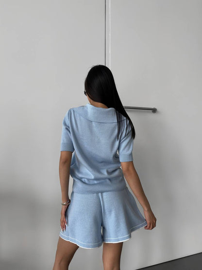 Person wearing a light blue tracksuit against a plain background