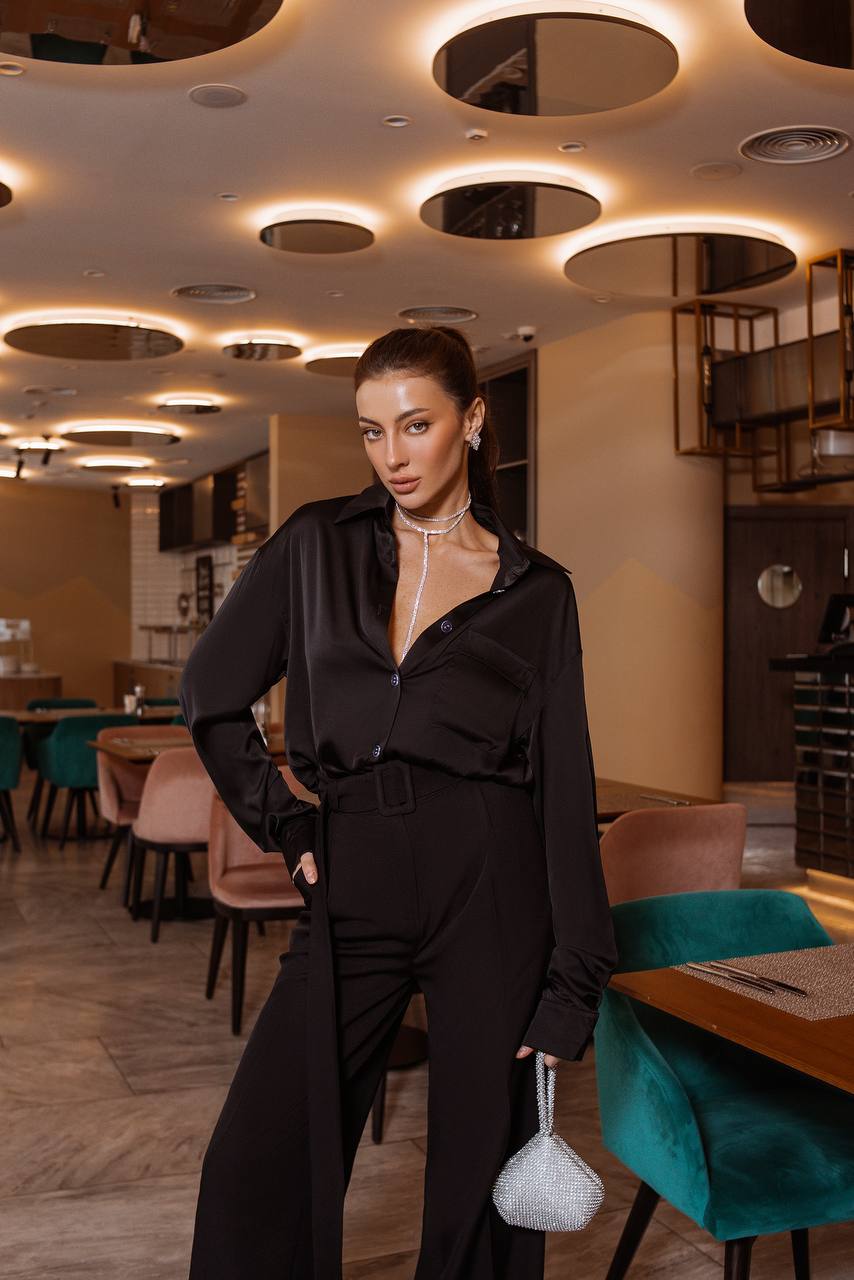 Woman in a black outfit standing in a modern restaurant with stylish interior design.