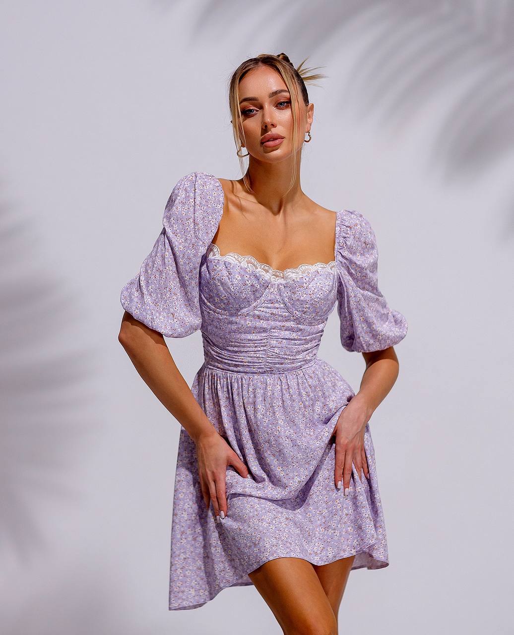 Woman wearing a light purple dress with puff sleeves against a plain background