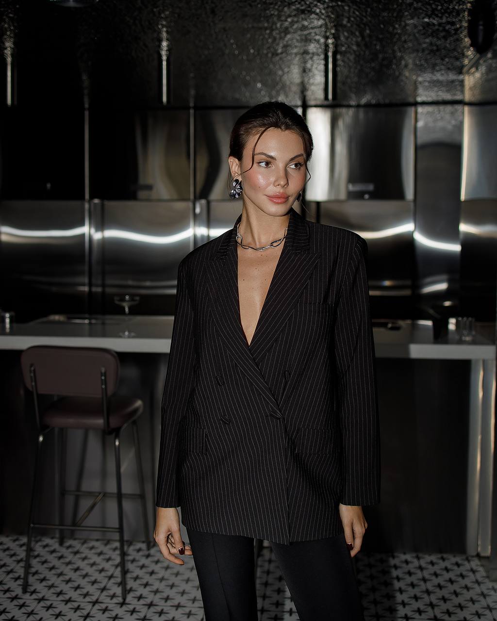 Woman wearing a black pinstripe suit in a modern interior setting