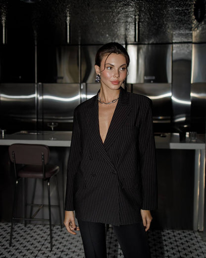 Woman wearing a black pinstripe suit in a modern interior setting