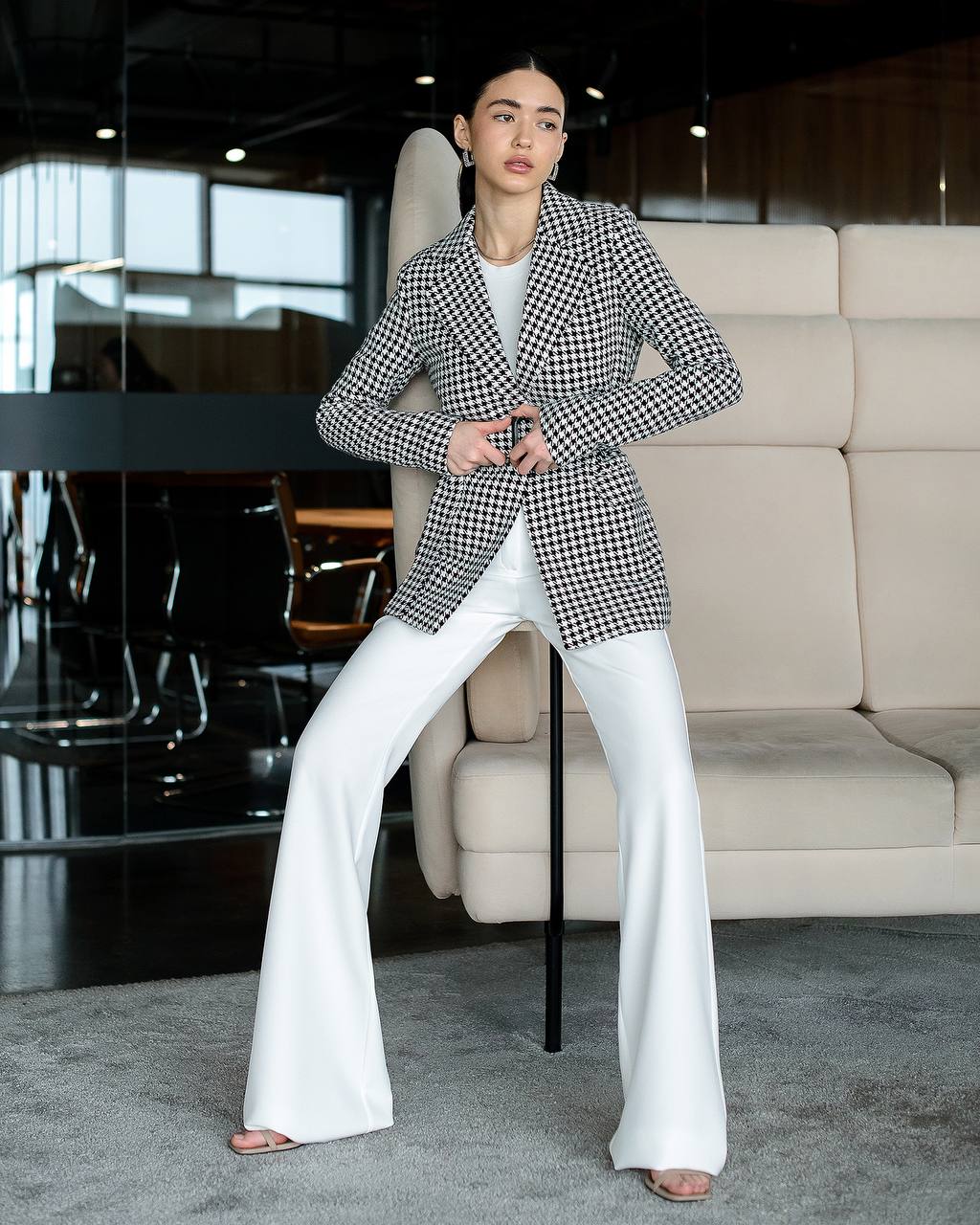 Person wearing a checkered blazer and white pants in an indoor setting