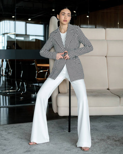Person wearing a checkered blazer and white pants in an indoor setting