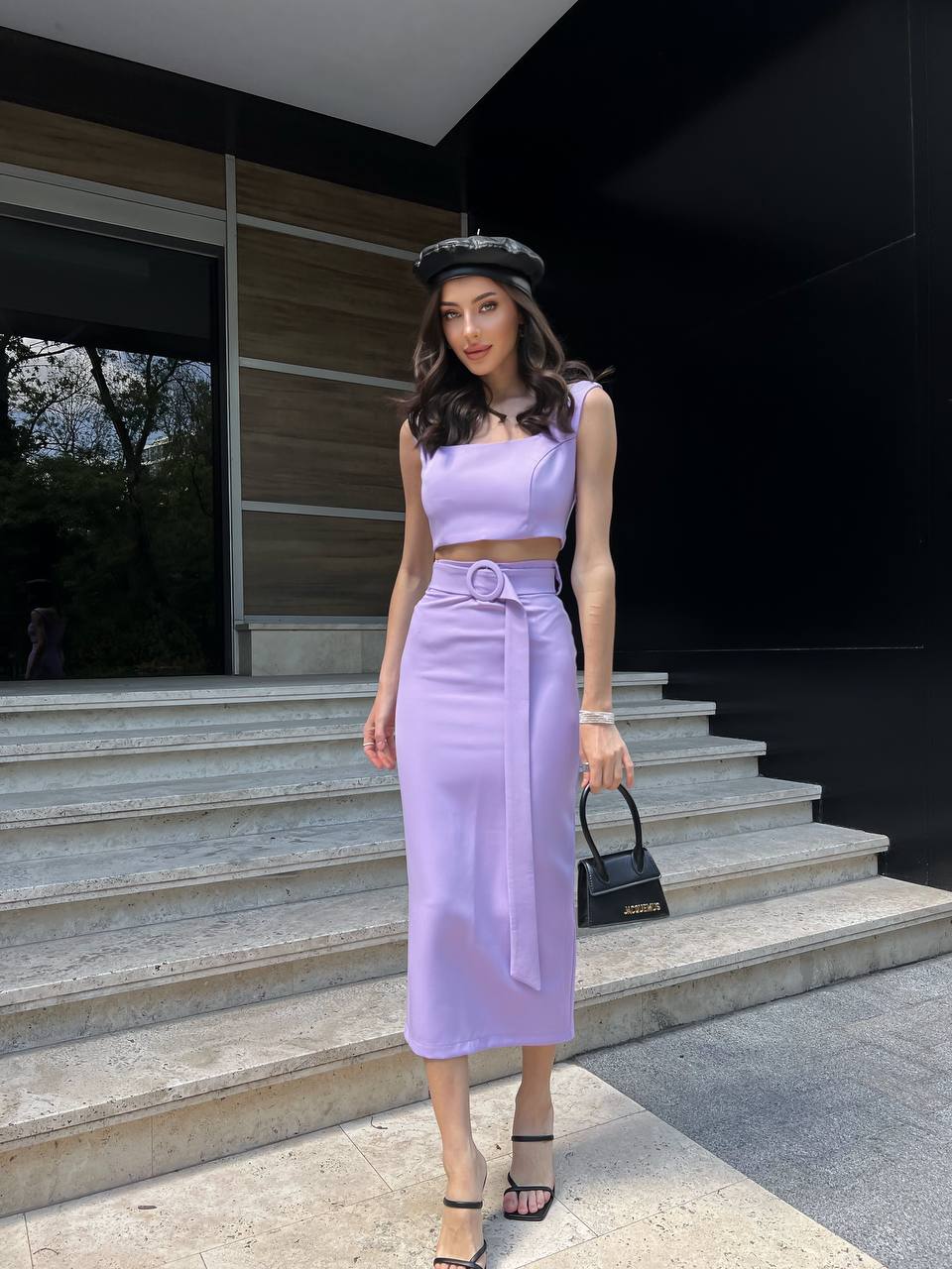 Woman in a lavender outfit standing on steps outside a modern building