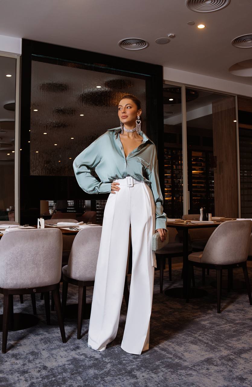 Woman in a stylish outfit standing in a modern restaurant.
